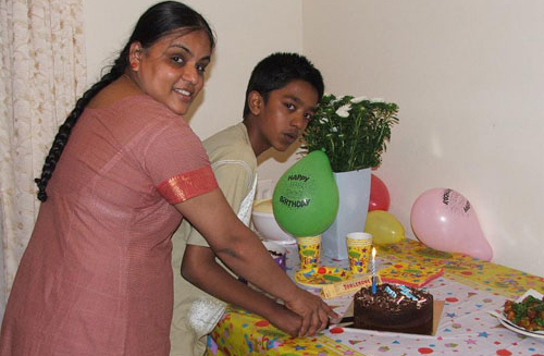 Ravi celebrating with family beside a cake.